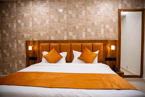 a bedroom with a large bed with orange pillows at Hotel Orange in Bhubaneshwar
