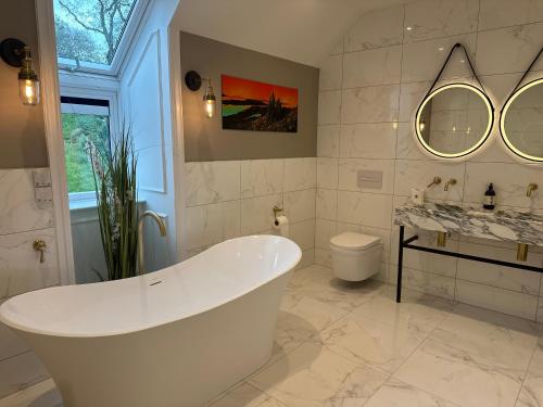 a white bathroom with a tub and a sink at Somerled House Suites in Portree