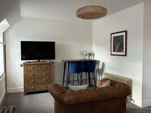 a living room with a couch and a flat screen tv at Somerled House Suites in Portree