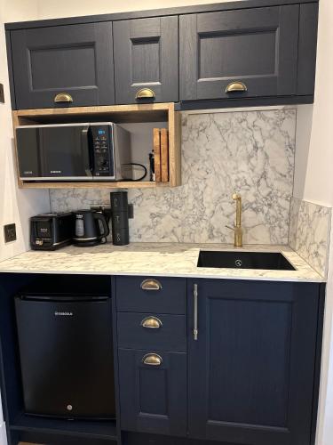 a kitchen with black cabinets and a sink and appliances at Somerled House Suites in Portree