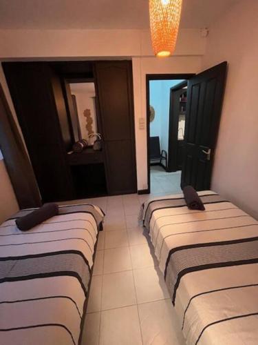 two beds lined up in a room with a hallway at Appartement Baobab 2 in Pereybere