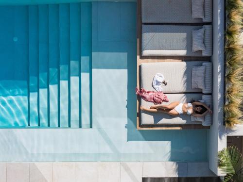 a woman sitting in a chair next to a swimming pool at Villa Kalōn in Rethymno Town