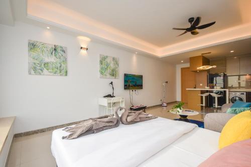 a living room with a white bed and a kitchen at R&F Princess Cove by Nest Home at Johor Bahru in Johor Bahru