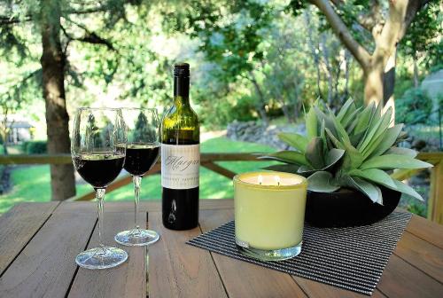 a bottle of wine and two glasses on a wooden table at Huntington Lodge and Cottage in Mount Tomah