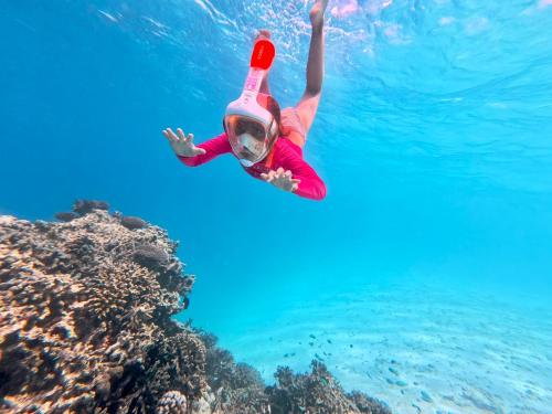 a woman is swimming in the water near a coral reef at Sabba Summer Suite , Fodhdhoo in Fodhdhoo