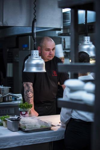 a man standing in a kitchen preparing food at Le Relais Des Trois Mas in Collioure