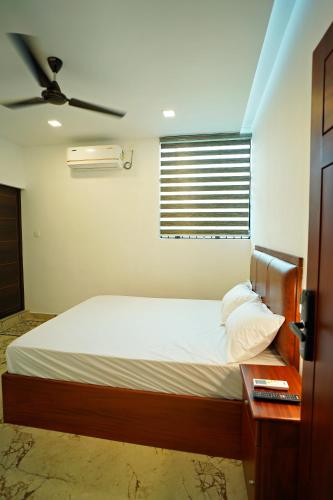 a bedroom with a bed with a fan and a table at GH Grand Park in Angamali