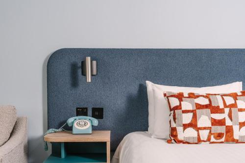 a bedroom with a bed with a clock on a table at voco Winchester Hotel & Spa by IHG in Winchester