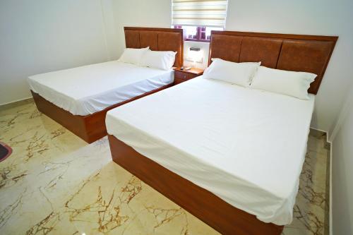 two beds in a hotel room with white sheets at GH Grand Park in Angamali