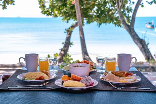a table with plates of food and drinks on the beach at Aonang Villa Resort l Lifestyle Beachfront Resort in Ao Nang Beach
