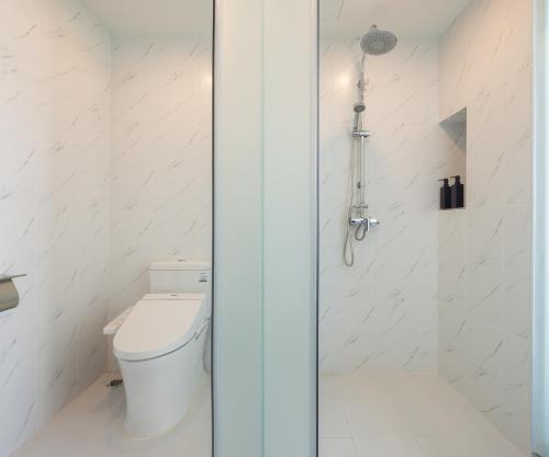 a white bathroom with a toilet and a shower at Hotel Selene Chiang Rai in Chiang Rai