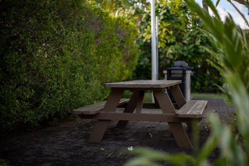 a wooden picnic table with an umbrella on a brick path at Plantation Hale Suites in Kapaa