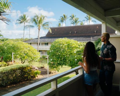 a man and a woman standing on a balcony looking at a building at Plantation Hale Suites in Kapaa