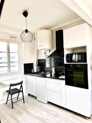- une cuisine avec des placards blancs et une chaise dans l'établissement Appartement vue tour Eiffel ligne 14 à côté de Paris, à Gentilly