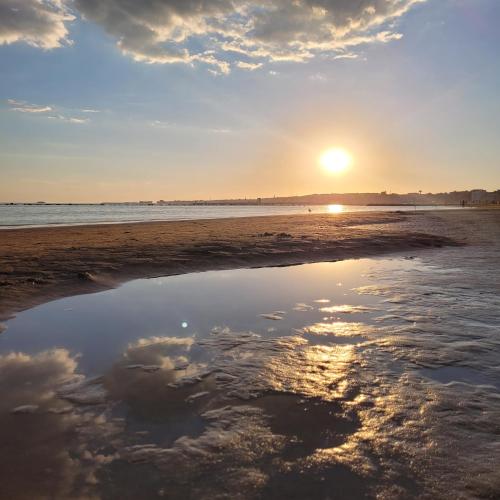 a reflection of the sunset on the beach at Sea la vie - Holiday house in Nettuno