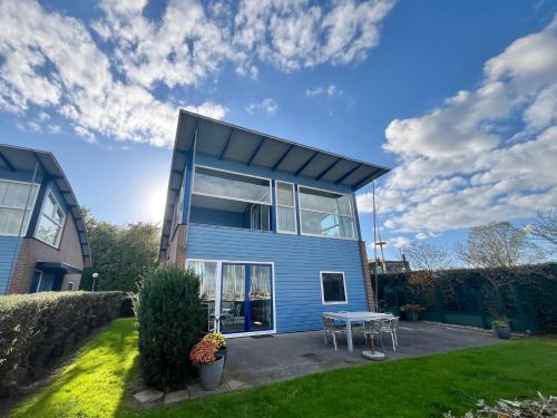 a blue house with a picnic table in a yard at 6pers Modern harbor house Jasmijn with fenced garden and lake view in Anjum