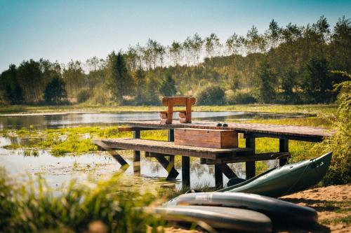 a wooden dock in a lake with a bench and two canoes at Ranczo Brusno in Połczyn-Zdrój