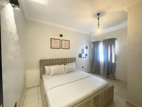 a bedroom with a bed with white sheets and a window at Stylish and Comfy 2 BR Apartment - Perfect for Families in Lagos