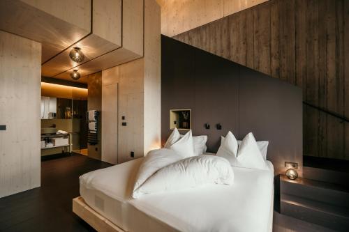 una camera da letto con un grande letto con cuscini bianchi di Green Luxury Hotel Pfösl a Nova Ponente