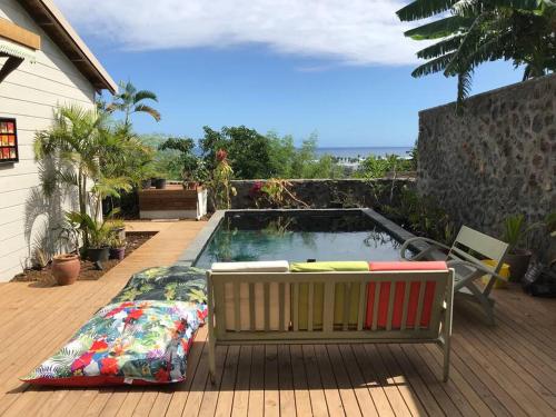 a swimming pool with a bench next to a house at Caze La Pointe Magnifique vue sur le Lagon in Saint-Paul