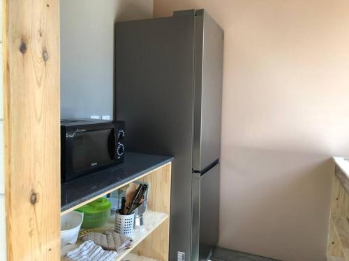 a stainless steel refrigerator with a microwave on a shelf at Caze La Pointe Magnifique vue sur le Lagon in Saint-Paul