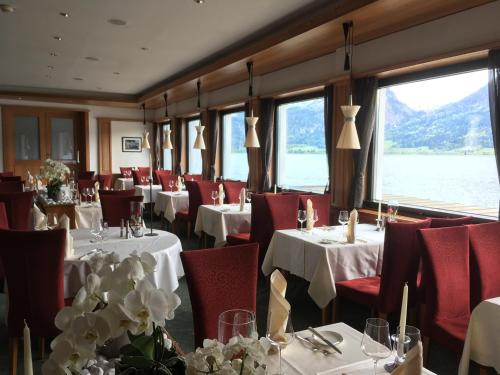 a restaurant with white tables and red chairs and windows at Romantik Hotel Im Weissen Rössl am Wolfgangsee in St. Wolfgang
