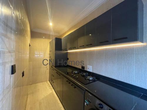 a kitchen with black cabinets and a counter top at Stylish and Comfy 2 BR Apartment - Perfect for Families in Lagos