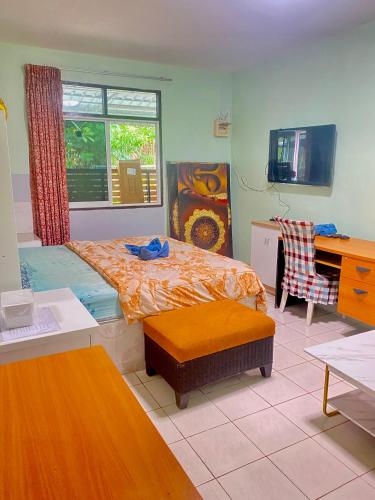 a bedroom with a bed and a desk and a window at Nan Inn Bungalow in Karon Beach
