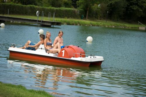 three people sitting on a boat in the water at Hotel Mönichwalderhof in Mönichwald