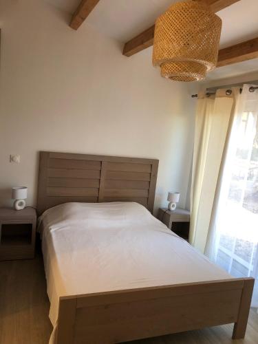 une chambre avec un grand lit et un lustre dans l'établissement Le Grenadier, à Ventenac-Cabardès