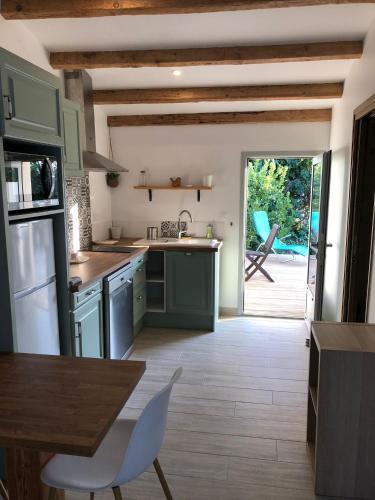 une cuisine avec des placards verts et une table ainsi qu'une terrasse dans l'établissement Le Grenadier, à Ventenac-Cabardès