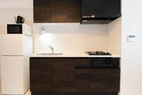 a kitchen with a white refrigerator and a sink at Metro Gate by Tranova in Tokyo