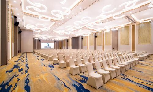 an empty room with white chairs and a stage at Guangzhou Southern Airlines Pearl Airport Hotel- Free shuttle bus to airport in Guangzhou