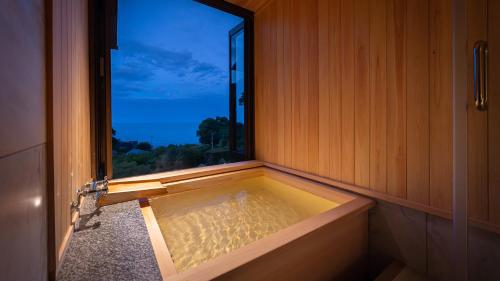 a bath tub in a room with a window at Isaribi (No Children) in Higashiizu