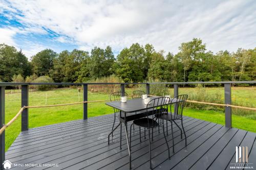 a wooden deck with a table and chairs on it at Holiday Hill Karpnki, Sauna, Domek Hygge-balia, Domek Lagom-jacuzzi in Karpniki