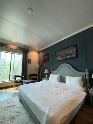 a bedroom with a large white bed with a blue wall at Hotel Swan Suites in Lahore