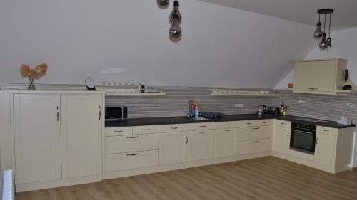 a kitchen with white cabinets and black counter tops at Residence Lhotka - Žďárské vrchy in Lhotka