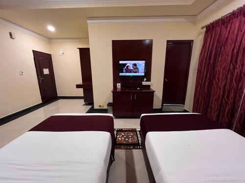 a hotel room with two beds and a television at Ananya Comfortss in Hospet