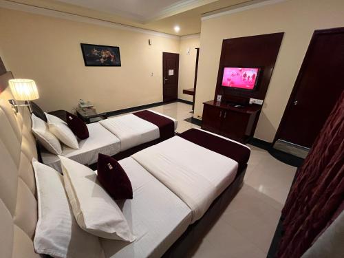 a hotel room with three beds and a flat screen tv at Ananya Comfortss in Hospet