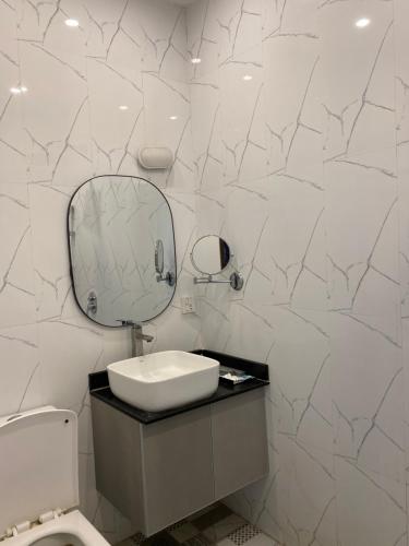 a white bathroom with a sink and a mirror at Hotel Swan Suites in Lahore