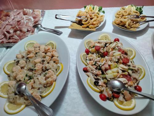 a table with plates of food with shrimp and other foods at Hotel Sporting in Casarsa della Delizia