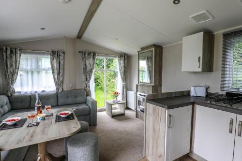 a kitchen and living room with a couch and a table at Tehidy Holiday Park in Illogan