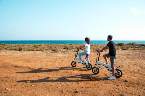 a man and woman riding scooters on the beach at Hotel Scoglio Degli Achei in Torre Santa Sabina