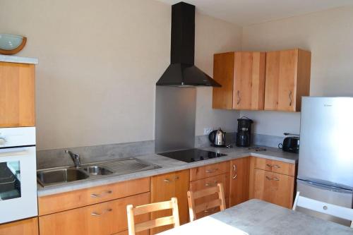 a kitchen with wooden cabinets and a sink and a refrigerator at Gîte entre terre et mer à Plouarzel in Plouarzel