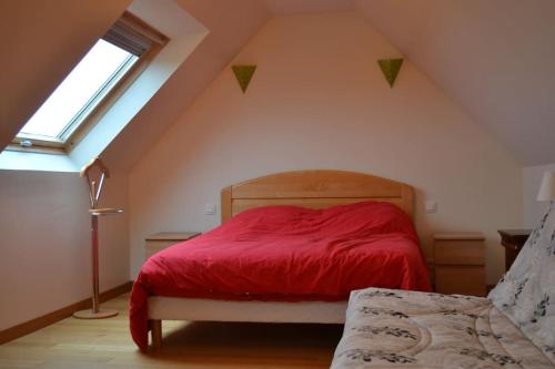 a bedroom with a red bed in a attic at Gîte entre terre et mer à Plouarzel in Plouarzel