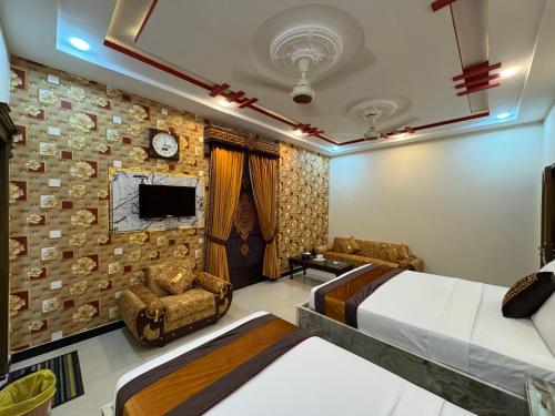 a bedroom with two beds and two chairs and a tv at Metro One Hotel in Lahore