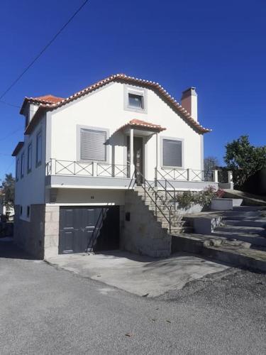 a large white house with a garage and stairs at Casa da Figueira in Novelães
