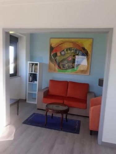 a living room with a red couch and a table at Casa da Figueira in Novelães