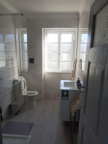 a bathroom with a toilet and a sink and a window at Casa da Figueira in Novelães