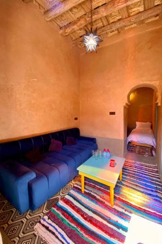 a living room with a blue couch and a table at Nomadic Birdway in Imiter